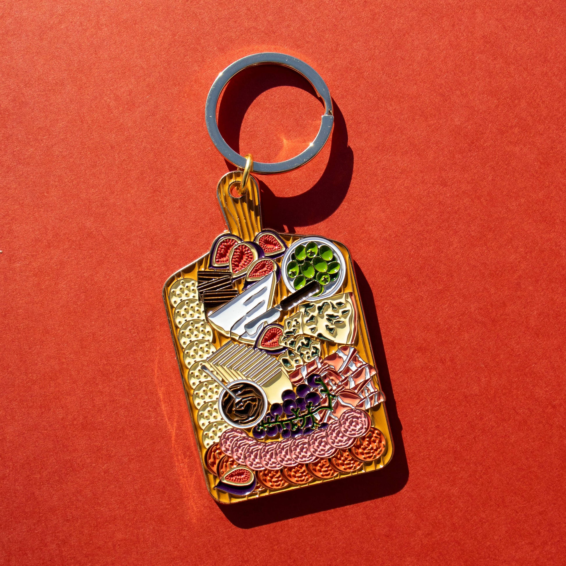 Charcuterie Board Keychain -- wooden board with crackers, various cured meats and cheeses, figs, olives and grapes
