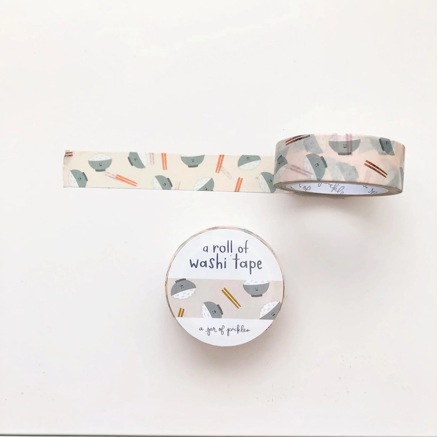 Unrolled washi tape with a bowl of rice and chopsticks as the print, with the front packaging of it shown below