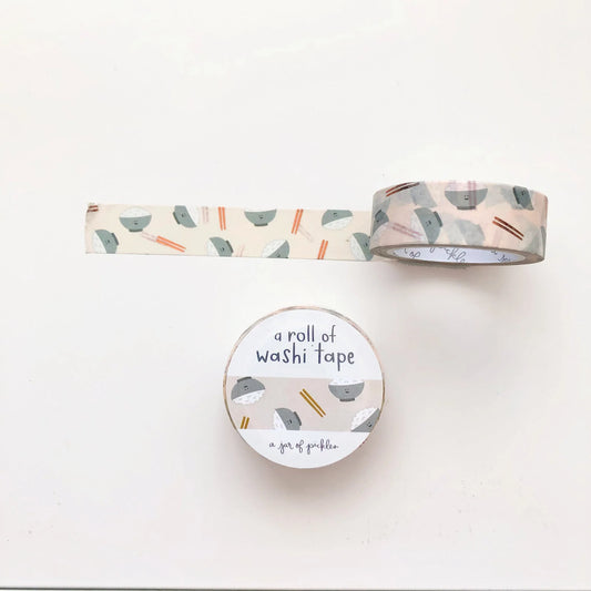 Unrolled washi tape with a bowl of rice and chopsticks as the print, with the front packaging of it shown below