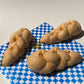 3 candles that look like Challah bread. Each candle has 3 wicks and are lit.