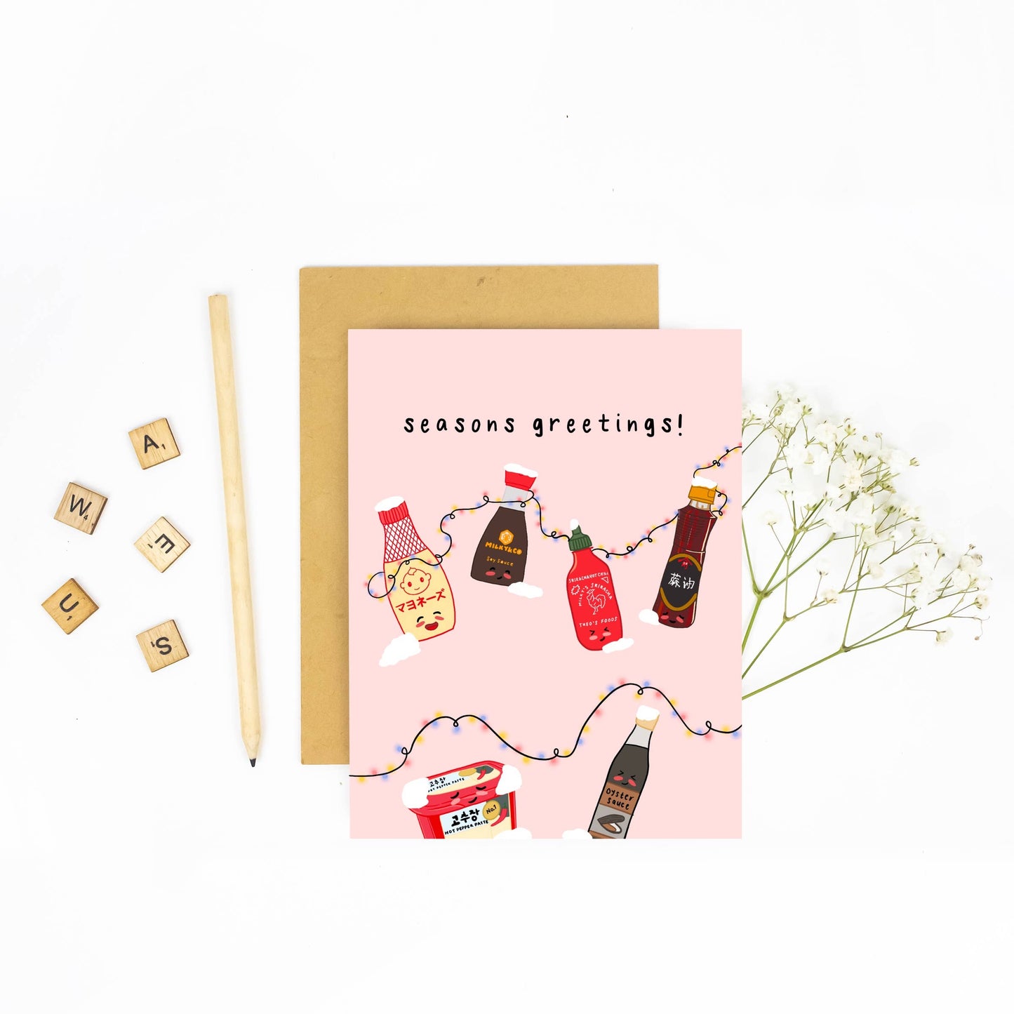 Holiday card with various asian seasoning sauces on it including kewpie mayo, soy sauce, sriracha, sesame oil, gochujang and oyster sauce. Black text reads "seasons greetings" 