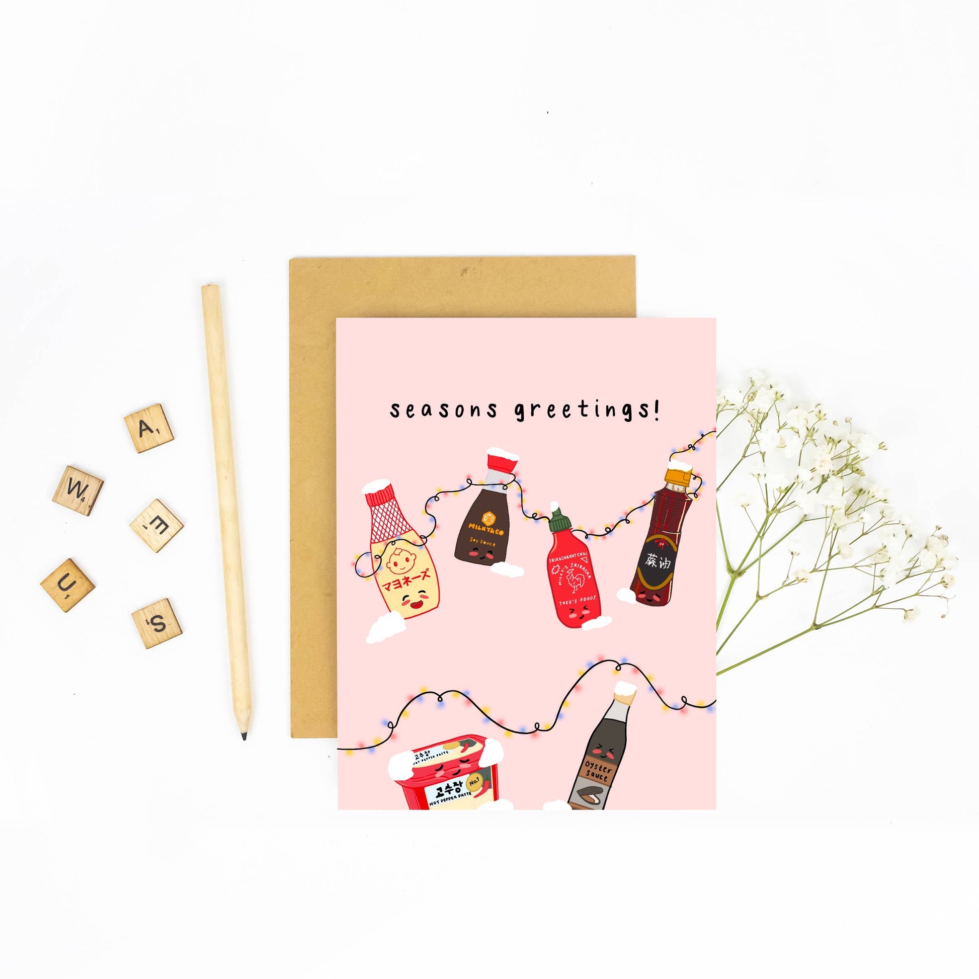 Holiday card with various asian seasoning sauces on it including kewpie mayo, soy sauce, sriracha, sesame oil, gochujang and oyster sauce. Black text reads "seasons greetings" 