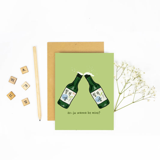 Light green greeting card with two soju fresh bottles clinking and text at the bottom that reads "so-ju wanna be mine?"