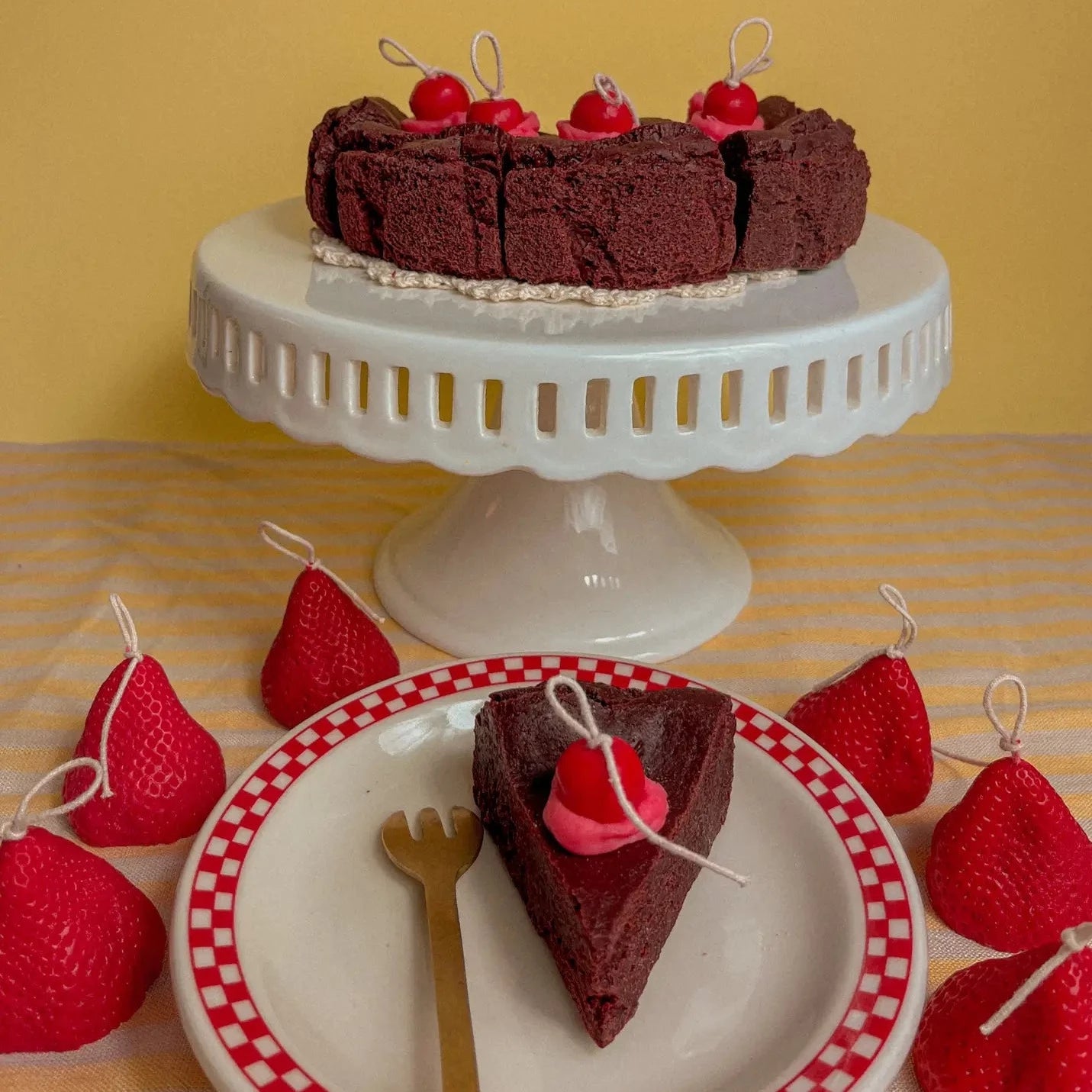 candle that looks and smells like a chocolate cake on a cake stand and plate 