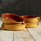 Four cazuelas; golden yellow on the outside, terracotta on the inside